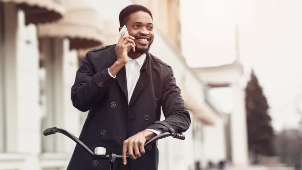 Homme d'affaires afro parlant au téléphone, debout avec vélo à l'extérieur — Photo