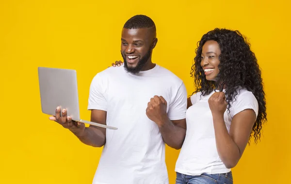 Feliz pareja negra celebrando el éxito con el ordenador portátil — Foto de Stock