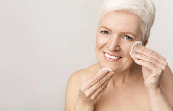 Signora anziana utilizzando tampone di cotone per rimuovere il trucco — Foto Stock