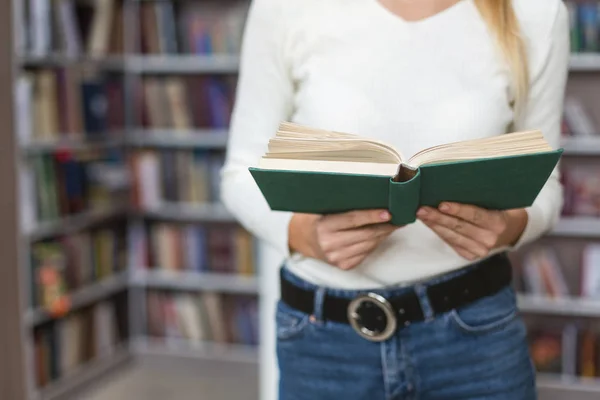 Menina caucasiana com livro aberto em pé na biblioteca — Fotografia de Stock