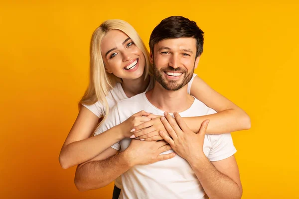 Sonriente pareja abrazando en amarillo estudio fondo — Foto de Stock