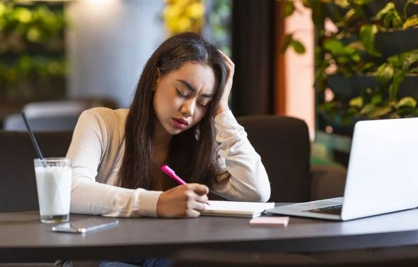 Cansado menina adolescente fazendo anotações enquanto estudava — Fotografia de Stock
