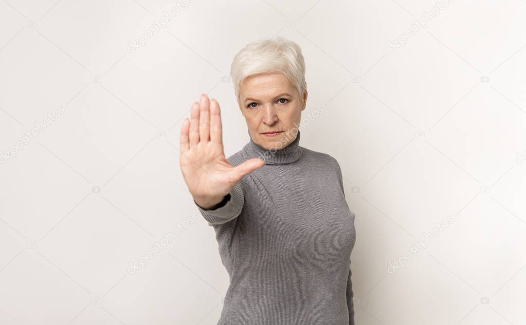 Portrait of serious elderly woman showing stop gesture with hand