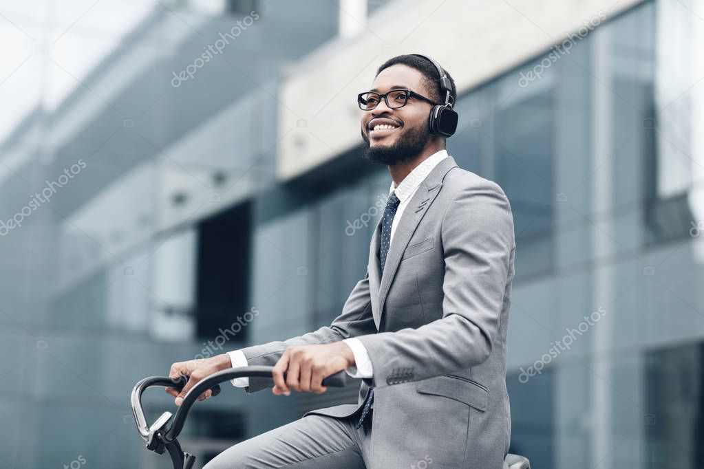 Way to work. Businessman riding on bike to work, listening music