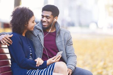 Afrikalı Amerikalı çift parkta telefonda müzik dinliyor