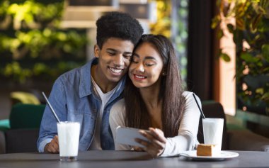 Kafede telefonla fotoğraf izleyen birkaç genç