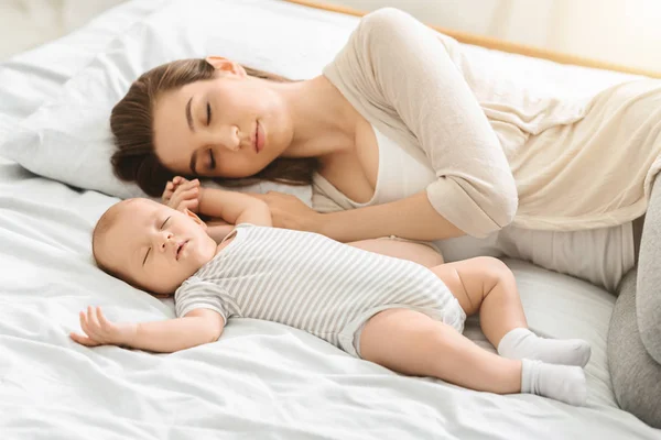 Trött mamma sover med sin nyfödda son, utmattad efter Babycare — Stockfoto