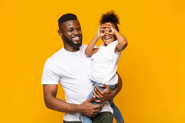 Hravý, malý Afro, který dělá brýle na prsty a žertoval na tatínkova — Stock fotografie