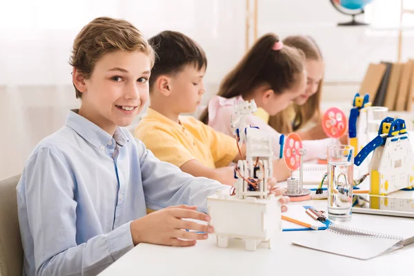 School jongen maken robot in Lab, glimlachend naar camera — Stockfoto