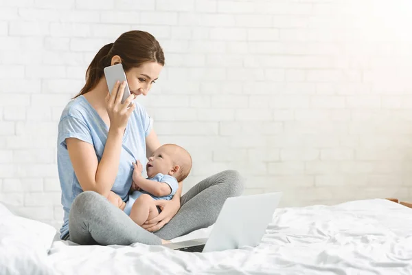 Fiatal anya beszél-ra mozgatható telefon és szoptatás újszülött gyermek — Stock Fotó