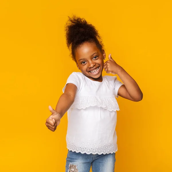 Bonito tímido pouco afro menina gestando polegares para cima e sorrindo — Fotografia de Stock