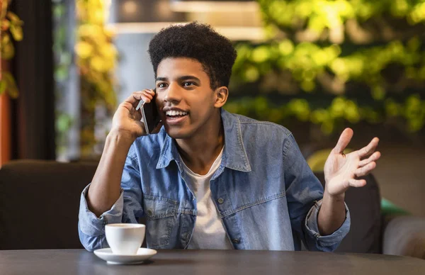 Érzelmi fekete srác beszél telefonon a cafeteria — Stock Fotó