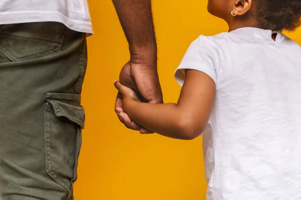 Liten afrikansk flicka som håller hennes pappa hand och tittar på honom — Stockfoto