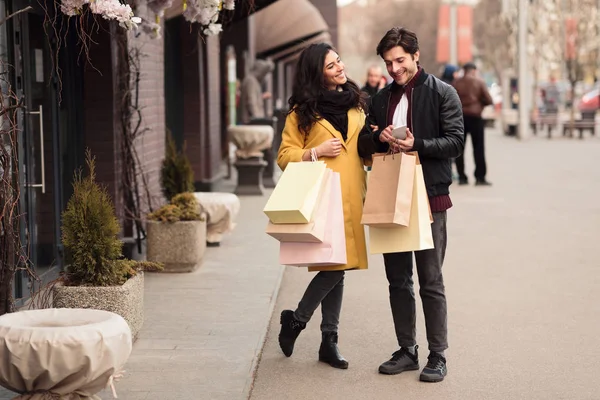 Concepto de consumismo. Pareja joven usando teléfono inteligente al aire libre — Foto de Stock