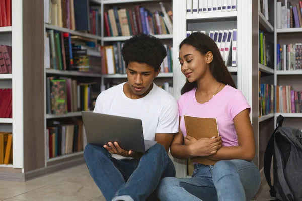 Casal de estudantes negros estudando no chão na biblioteca — Fotografia de Stock