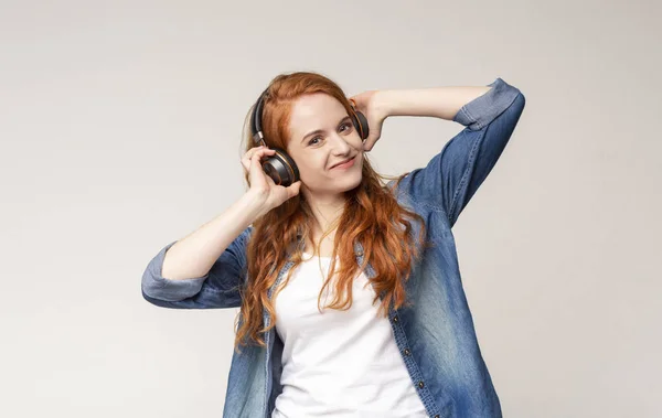 Joyful pelirroja adolescente disfrutando de escuchar música en auriculares inalámbricos — Foto de Stock