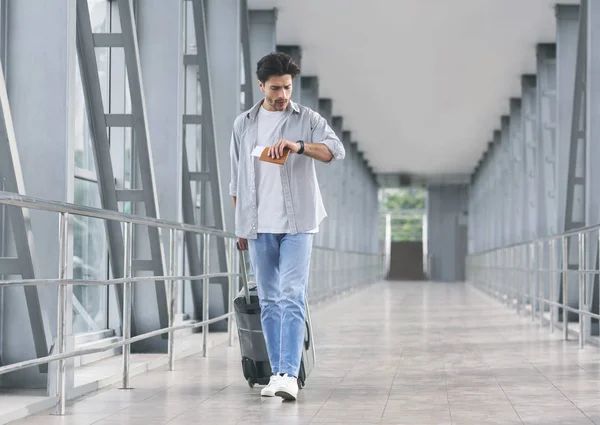 Bezorgd toeristische controletijd op horloge, gaan in de luchthaven loopbrug — Stockfoto