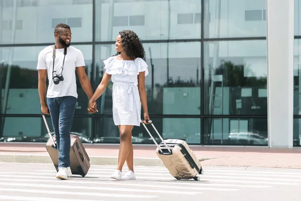 Feliz preto millennials saindo do aeroporto com bagagem — Fotografia de Stock