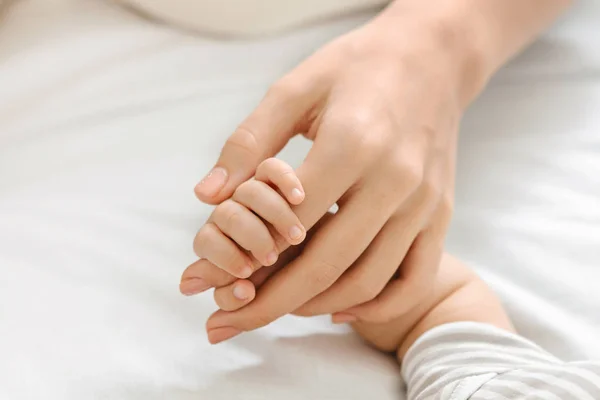 Minúsculos dedos de bebê recém-nascido segurando as mães mão, close-up — Fotografia de Stock