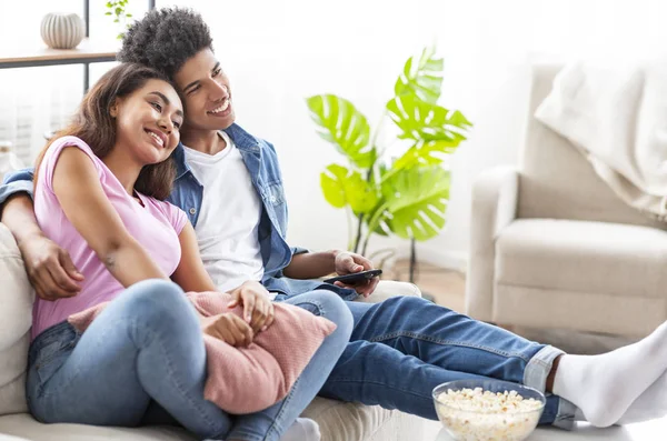 黑人青少年夫妇看电视，坐在沙发上爆米花在家里，自由空间 — 图库照片