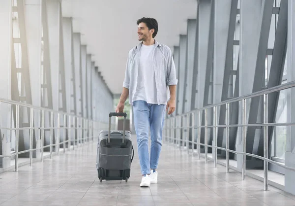Young man walking in airport walkway with luggage