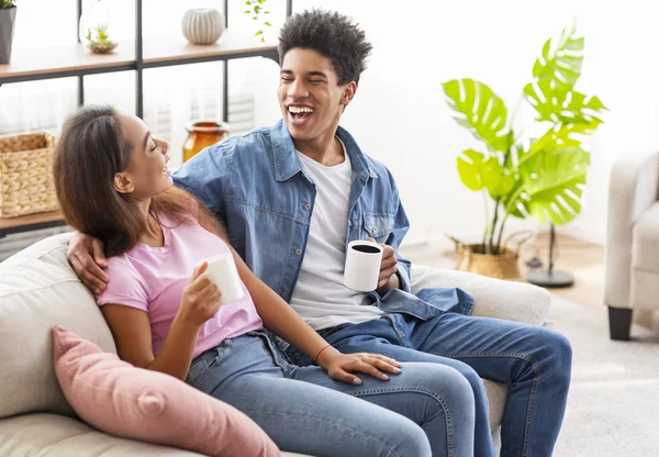 Adolescentes alegres tomando café y riendo mientras están sentados en casa —  Fotos de Stock