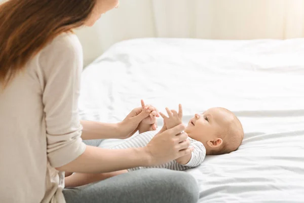 Bedårande nyfödda pojke leker med mamma i sängen — Stockfoto