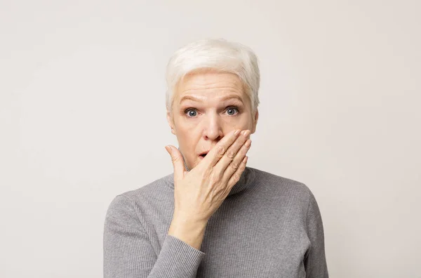 Shocked senior lady covering her mouth with hand — Stock Photo, Image