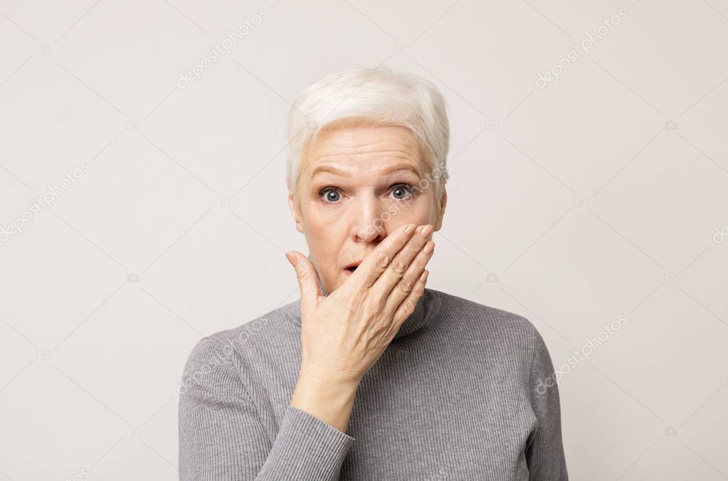 Shocked senior lady covering her mouth with hand