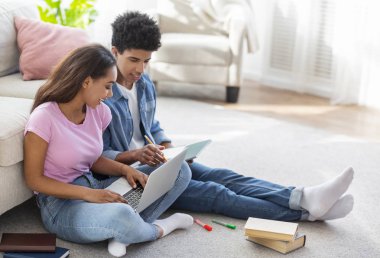 Siyah gençler dizüstü bilgisayar kullanarak katta oturan, evde eğitim