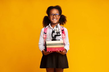Afro Schoolgirl Holding Mikroskop Ve Kitap Yığını, Sarı Arka Plan