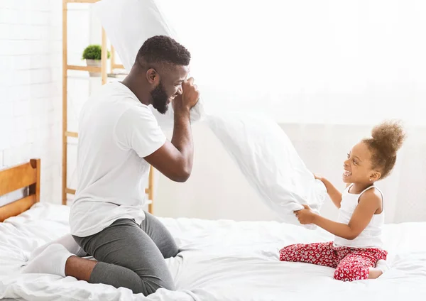 Africano pai e pequena filha tendo travesseiro luta na cama — Fotografia de Stock