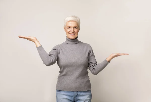 Oudere vrouw vergelijkt varianten, maakt weegschalen met haar lege handen — Stockfoto