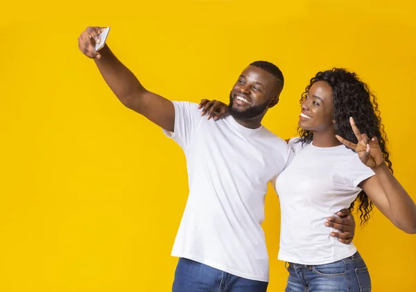 Preto casal no amor fazendo selfie sobre amarelo estúdio fundo — Fotografia de Stock