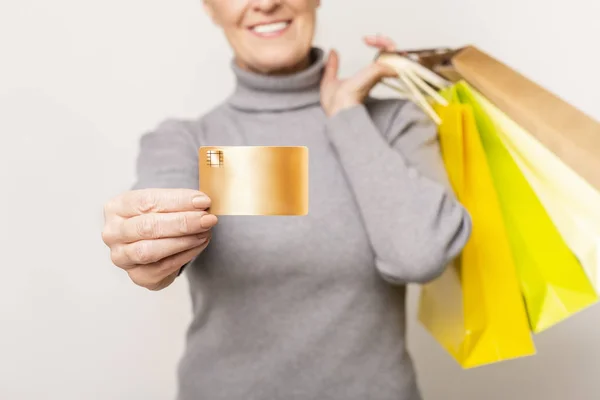 クレジットカードとカラフルなショッピングバッグを持つ喜ばしいシニア女性 — ストック写真