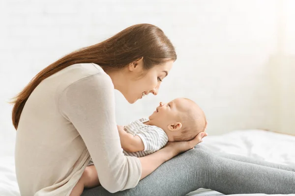 Genç anne yatakta sevimli bebek ile oynuyor — Stok fotoğraf