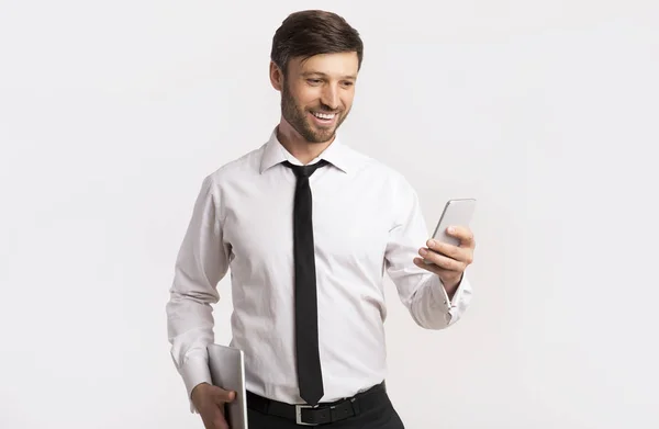 Glücklicher Mann mit Handy hält Tablet auf weißem Studiohintergrund — Stockfoto