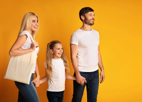 Padres e hija caminando con las manos en el fondo amarillo — Foto de Stock