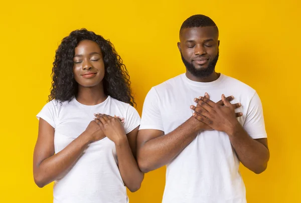 Серьезный афро-мужчина и женщина возлагают руки на свои сердца — стоковое фото