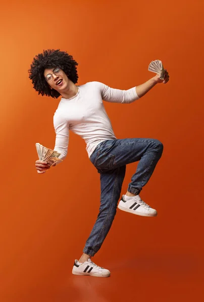 Эмоциональный африканский мужчина танцует с кучей долларов — стоковое фото