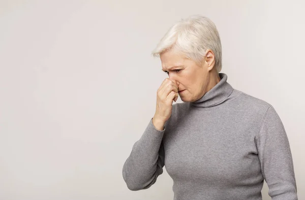 Senior Kvinna stänger näsa på grund av dålig lukt — Stockfoto