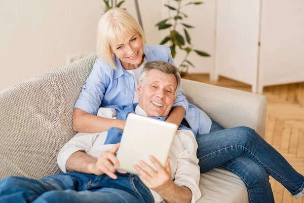Šťastné dospívající manželé používající tablet, relaxace na pohovce — Stock fotografie
