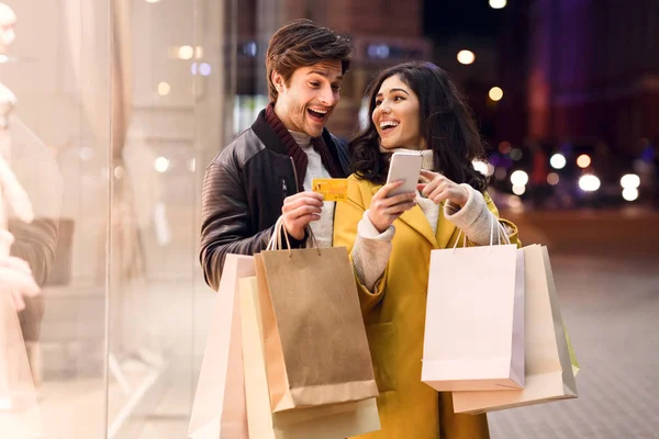 Consumerism-concept. Gelukkige paar het controleren van de mobiele telefoon buitenshuis — Stockfoto