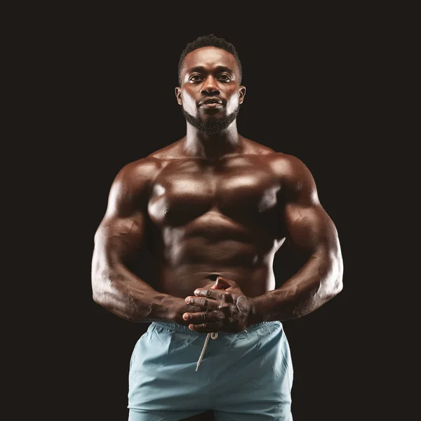 Retrato de deportista musculoso demostrando su cuerpo sobre fondo negro — Foto de Stock