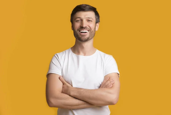 Feliz hombre de mediana edad riendo cruzando las manos sobre fondo amarillo — Foto de Stock