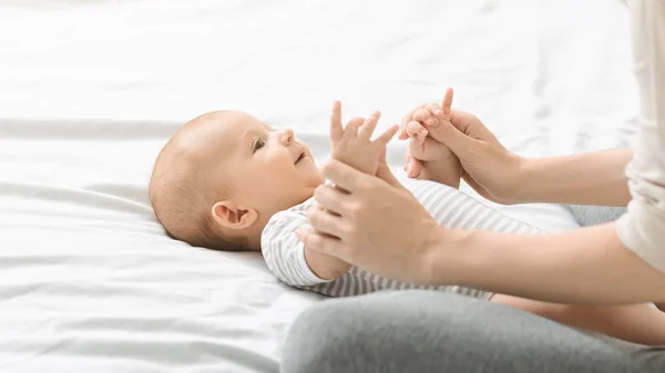 Mother massaging cute newborn baby, doing exercises for his development. — Stock Photo, Image