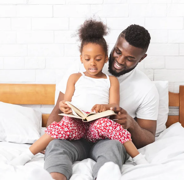 Africano americano homem lendo livro com sua filhinha bonito — Fotografia de Stock