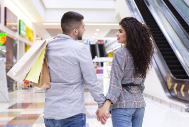 Şehir merkezinde alışveriş poşetleri ile yürüyen sevgi dolu çift