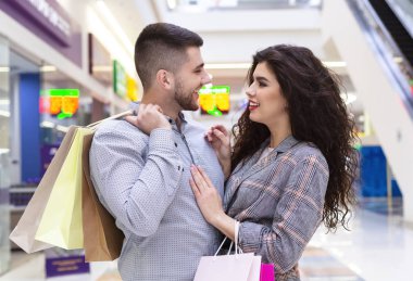 Alışveriş merkezinde birlikte alışveriş yaptıktan sonra kucaklayan mutlu çift