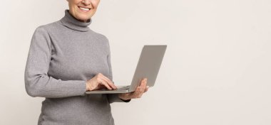 Tanınmayan yaşlı kadın dizüstü bilgisayar tutan, ışık stüdyo arka plan üzerinde duran